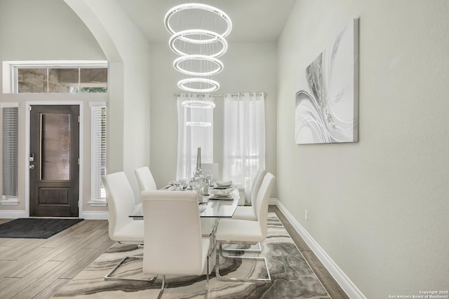 8823 Hideout, San Antonio, TX 78254 - dining space featuring wood finished floors, baseboards, arched walkways, and a chandelier