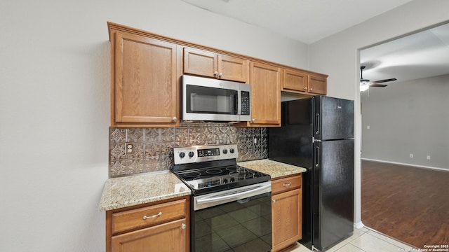 2253 Hidden Mdw, New Braunfels, TX 78130 - kitchen with appliances with stainless steel finishes, backsplash, ceiling fan, light stone countertops, and light tile patterned floors