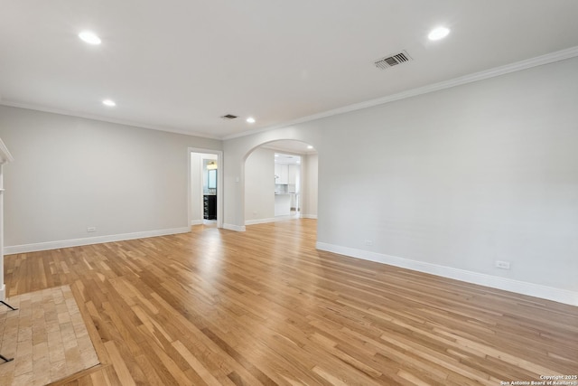 129 Elmview, Alamo Heights, TX 78209 - unfurnished living room with arched walkways, crown molding, recessed lighting, light wood-style flooring, and baseboards