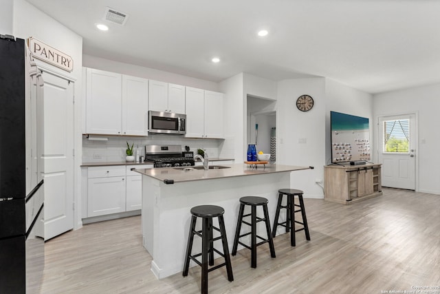 6718 Carlton Crst, San Antonio, TX 78253 - kitchen with stainless steel appliances, a sink, a kitchen breakfast bar, light wood-type flooring, and tasteful backsplash