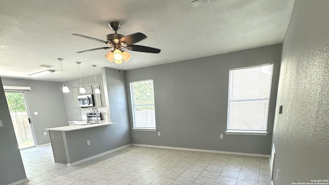 6711 Dragon Tooth, San Antonio, TX 78242 - kitchen featuring stainless steel appliances, ceiling fan, light countertops, a peninsula, and a textured ceiling