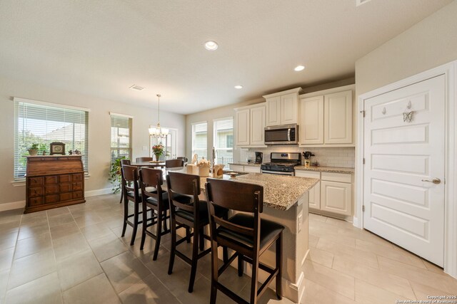 9334 Sundrop, San Antonio, TX 78254 - kitchen with appliances with stainless steel finishes, a chandelier, tasteful backsplash, light tile patterned floors, and light stone counters