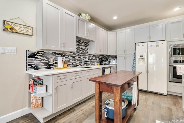 573 Mountain Oaks Dr, Canyon Lake, TX 78133 - kitchen featuring appliances with stainless steel finishes, a sink, light countertops, light wood-type flooring, and tasteful backsplash