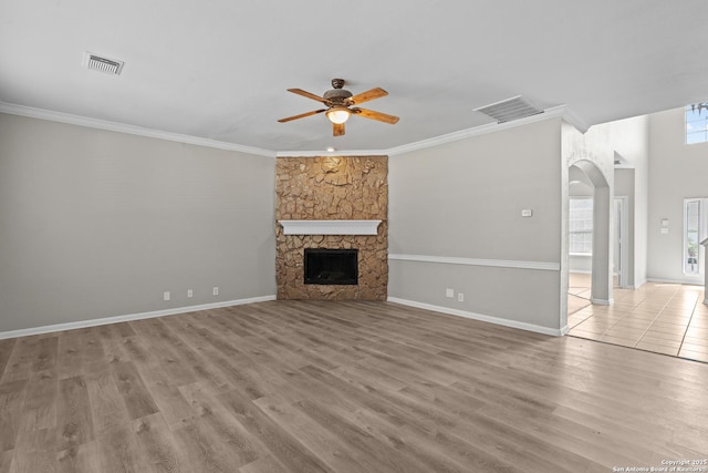 25233 Battle Lk, San Antonio, TX 78260 - unfurnished living room featuring ceiling fan, arched walkways, wood finished floors, a stone fireplace, and crown molding