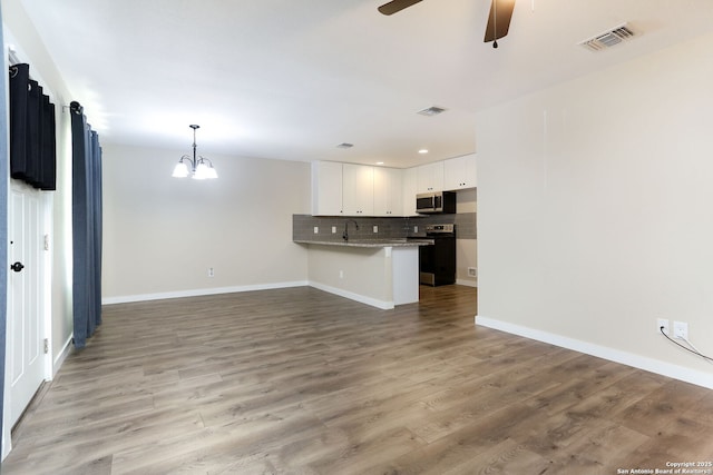 239 Surrey, San Antonio, TX 78225 - unfurnished living room with a chandelier, ceiling fan, light wood-style floors, baseboards, and recessed lighting