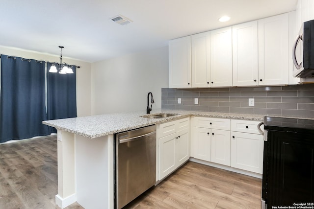 239 Surrey, San Antonio, TX 78225 - kitchen with dishwasher, a sink, light wood-style flooring, a chandelier, and a peninsula