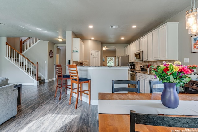 214 Ridge Blf, Cibolo, TX 78108 - kitchen with stainless steel appliances, dark wood-type flooring, white cabinetry, arched walkways, and recessed lighting