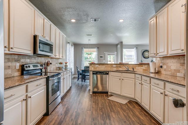214 Ridge Blf, Cibolo, TX 78108 - kitchen featuring stainless steel appliances, a peninsula, a sink, dark wood-style flooring, and a textured ceiling