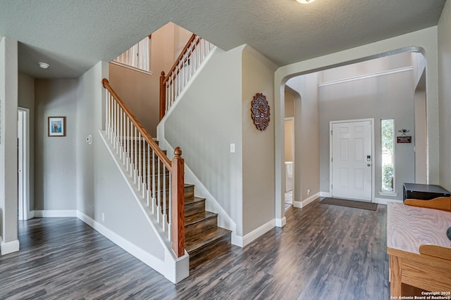 214 Ridge Blf, Cibolo, TX 78108 - entryway with arched walkways, dark wood-style flooring, baseboards, stairway, and a textured ceiling