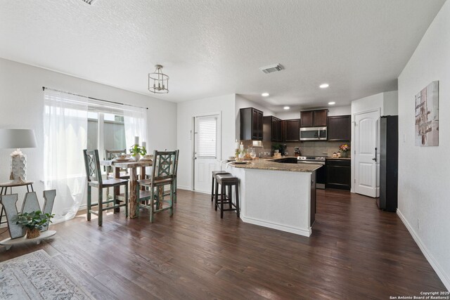 184 Jolie Cir, Boerne, TX 78015 - kitchen with appliances with stainless steel finishes, a peninsula, dark brown cabinetry, dark wood-type flooring, and baseboards