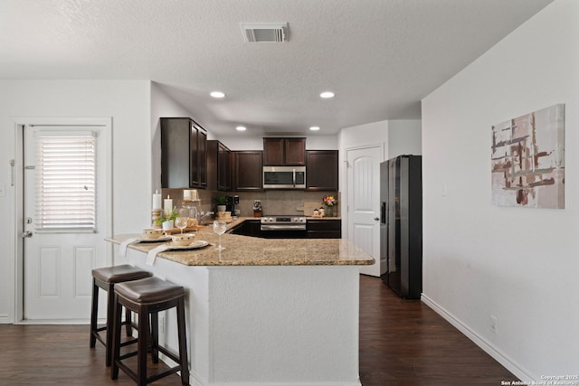 184 Jolie Cir, Boerne, TX 78015 - kitchen featuring appliances with stainless steel finishes, dark brown cabinetry, a peninsula, dark wood-style floors, and a textured ceiling