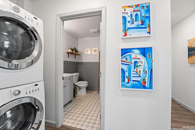 351 Barbara, San Antonio, TX 78216 - laundry area with stacked washer and clothes dryer, tile patterned floors, and wainscoting