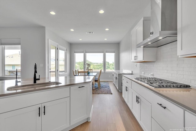 1624 Dirndl, New Braunfels, TX 78132 - kitchen featuring a sink, wall chimney exhaust hood, stainless steel gas stovetop, light wood-type flooring, and white cabinets