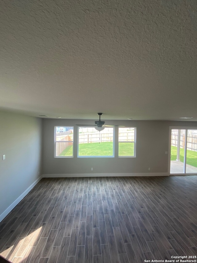 11111 Carlyle Spgs, Live Oak, TX 78233 - empty room featuring baseboards, dark wood finished floors, healthy amount of natural light, and a textured ceiling