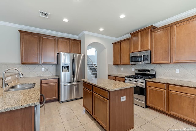 23022 Airedale Ln, San Antonio, TX 78260 - kitchen featuring appliances with stainless steel finishes, a sink, arched walkways, light stone counters, and crown molding