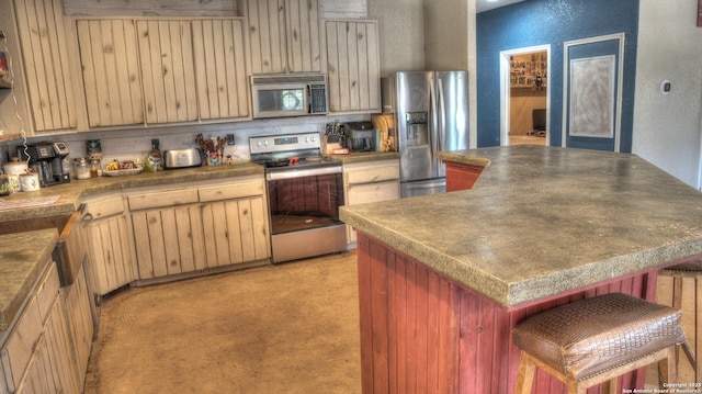 121 David Rankin Rd, Leakey, TX 78873 - kitchen featuring appliances with stainless steel finishes, a textured wall, a kitchen island, dark countertops, and light brown cabinets