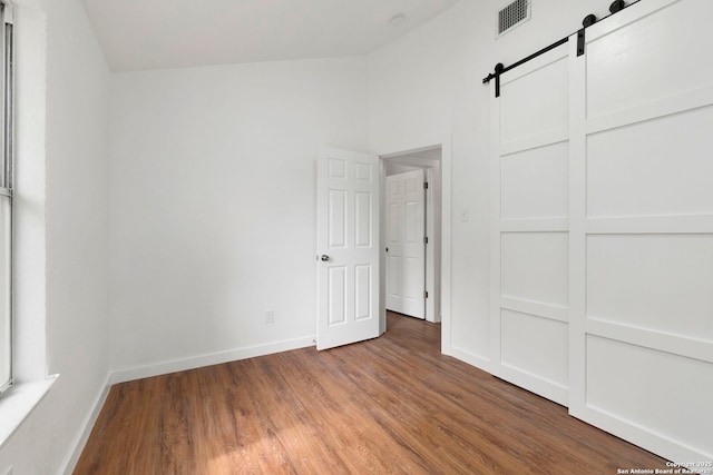 10707 Musket, San Antonio, TX 78224 - unfurnished bedroom featuring a barn door, wood finished floors, and baseboards
