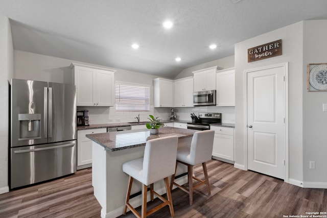 6038 Ballast Trl, New Braunfels, TX 78132 - kitchen featuring stainless steel appliances, wood finished floors, a kitchen island, a breakfast bar area, and white cabinetry