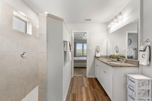 6038 Ballast Trl, New Braunfels, TX 78132 - full bathroom featuring connected bathroom, wood finished floors, a ceiling fan, double vanity, and a walk in shower
