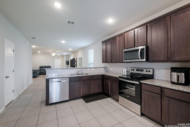 7731 Chatham, San Antonio, TX 78218 - kitchen with stainless steel appliances, a sink, dark brown cabinets, open floor plan, and a peninsula