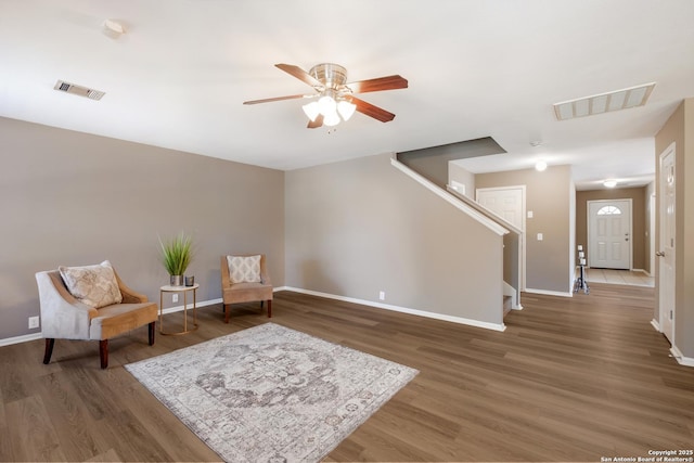 living area featuring baseboards, wood finished floors, stairs, and a ceiling fan