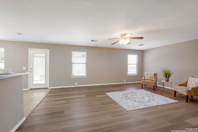 living area with plenty of natural light, ceiling fan, light wood-type flooring, and baseboards
