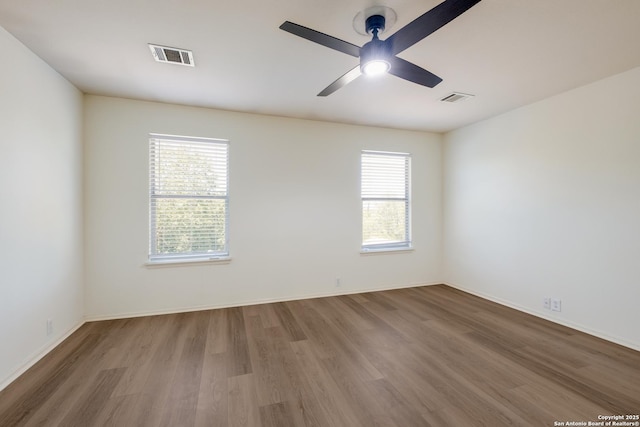 unfurnished room with wood finished floors, a ceiling fan, and baseboards