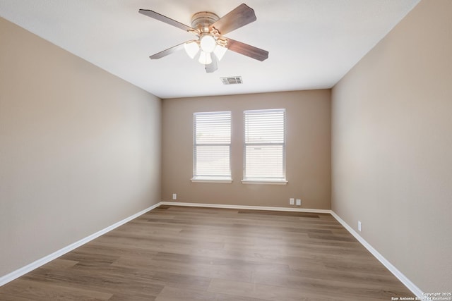spare room featuring wood finished floors, ceiling fan, and baseboards