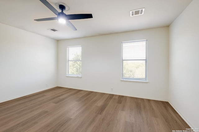 unfurnished room with wood finished floors, a ceiling fan, and baseboards