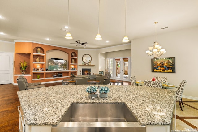 28914 Gracies Sky, San Antonio, TX 78260 - kitchen featuring a sink, a center island with sink, baseboards, a warm lit fireplace, and light stone counters