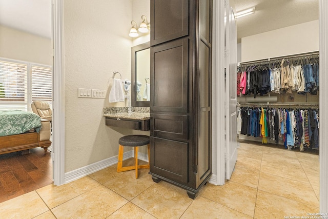 28914 Gracies Sky, San Antonio, TX 78260 - bathroom with a textured wall, tile patterned flooring, a walk in closet, and baseboards