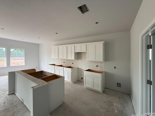 13726 Birch Xing, San Antonio, TX 78252 - kitchen with a textured ceiling, white cabinetry, decorative backsplash, and a kitchen island