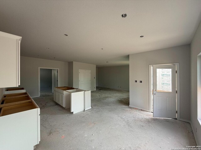13726 Birch Xing, San Antonio, TX 78252 - kitchen featuring white cabinetry, a kitchen island, open floor plan, and baseboards
