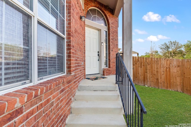 property entrance featuring brick siding and fence