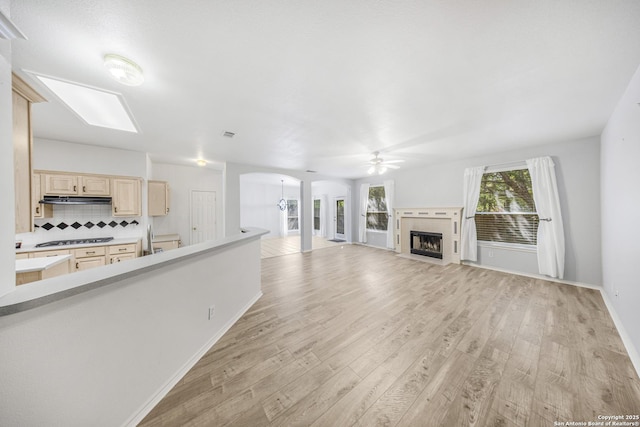 4726 Shavano Bark, San Antonio, TX 78230 - unfurnished living room with a ceiling fan, light wood-style floors, a tiled fireplace, and arched walkways