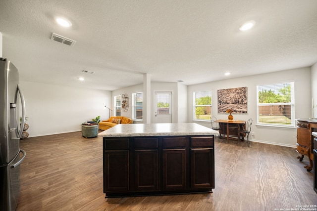 9827 Western Sedge, San Antonio, TX 78254 - kitchen featuring stainless steel fridge with ice dispenser, wood finished floors, baseboards, recessed lighting, and a kitchen island