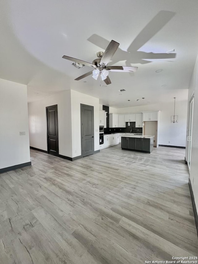 6427 Ridge Cir, San Antonio, TX 78233 - unfurnished living room featuring baseboards, ceiling fan, and light wood finished floors