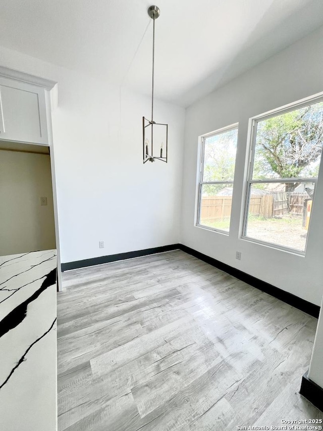 6427 Ridge Cir, San Antonio, TX 78233 - unfurnished dining area with a chandelier, light wood-type flooring, and baseboards