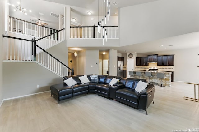 6739 Indian, San Antonio, TX 78253 - living area featuring light wood-style floors, a ceiling fan, stairway, a high ceiling, and baseboards