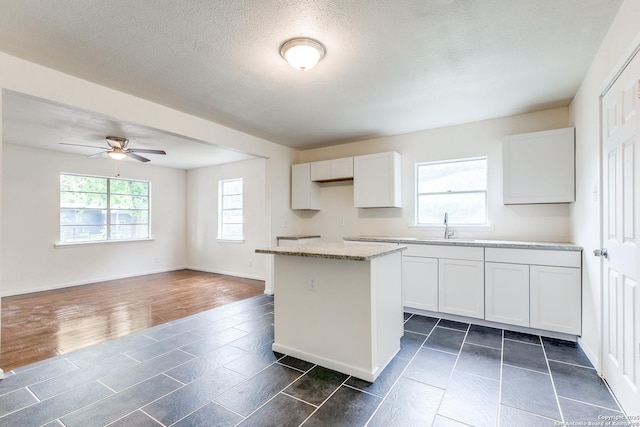 1319 Keats, San Antonio, TX 78211 - kitchen featuring a ceiling fan, a kitchen island, a sink, white cabinets, and a textured ceiling