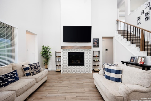 807 Swenson Rnch, San Antonio, TX 78245 - living room featuring a towering ceiling, stairway, light wood-type flooring, and a tiled fireplace