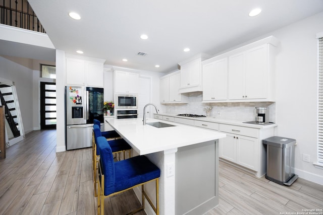 807 Swenson Rnch, San Antonio, TX 78245 - kitchen featuring appliances with stainless steel finishes, a sink, light wood finished floors, backsplash, and white cabinets