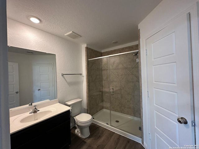 1116 Eagle, Seguin, TX 78155 - bathroom featuring wood finished floors, a stall shower, toilet, vanity, and a textured ceiling