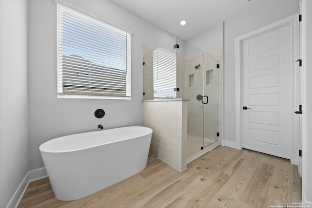 207 Azalea Aly, Castroville, TX 78009 - bathroom featuring wood finished floors, a freestanding bath, a stall shower, and baseboards