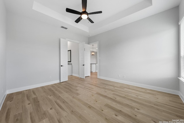 191 Azalea Aly, Castroville, TX 78009 - unfurnished bedroom with a tray ceiling, light wood-type flooring, baseboards, and ceiling fan