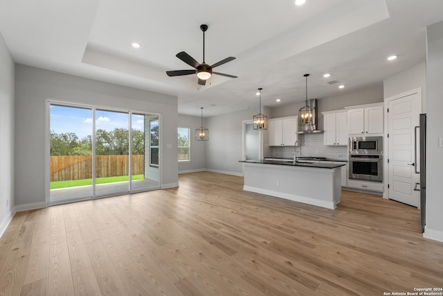191 Azalea Aly, Castroville, TX 78009 - kitchen featuring appliances with stainless steel finishes, dark countertops, wall chimney exhaust hood, open floor plan, and baseboards