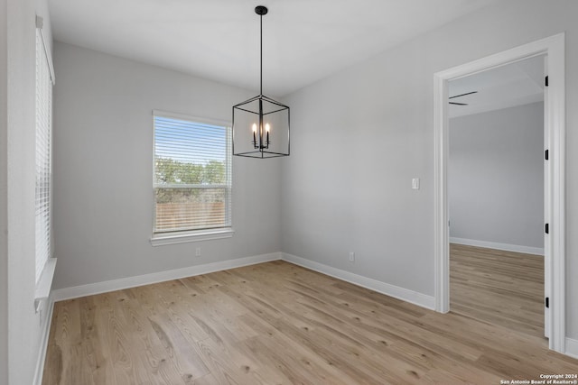 191 Azalea Aly, Castroville, TX 78009 - unfurnished dining area featuring light wood-type flooring, a chandelier, and baseboards