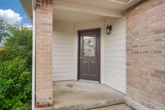 doorway to property featuring brick siding