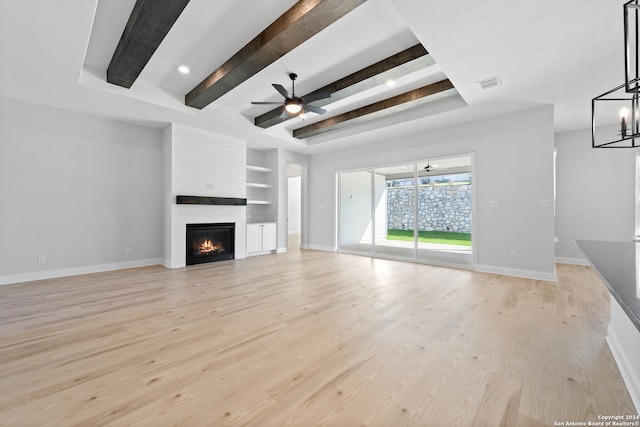 243 Wisteria Vw, Castroville, TX 78009 - unfurnished living room featuring baseboards, a large fireplace, a ceiling fan, light wood-style floors, and beamed ceiling