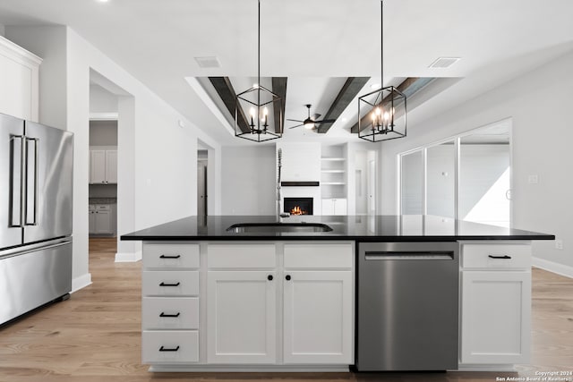 243 Wisteria Vw, Castroville, TX 78009 - kitchen with appliances with stainless steel finishes, a chandelier, dark countertops, light wood-style flooring, and white cabinets